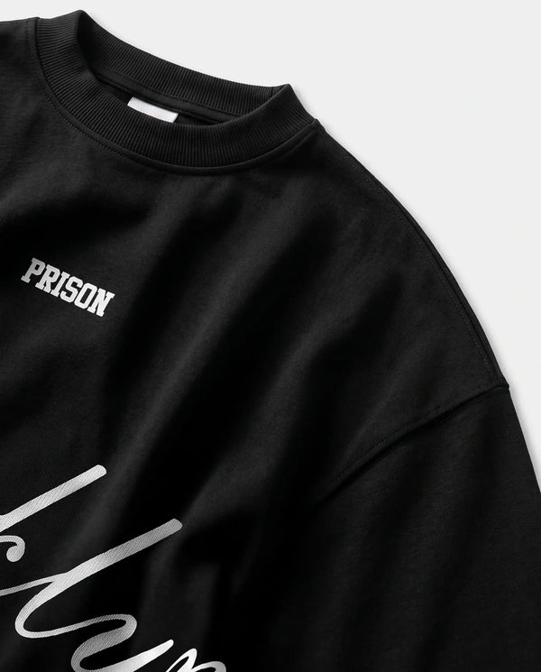 Detalhe da gola canelada e do ombro caído da camiseta oversized preta Prison