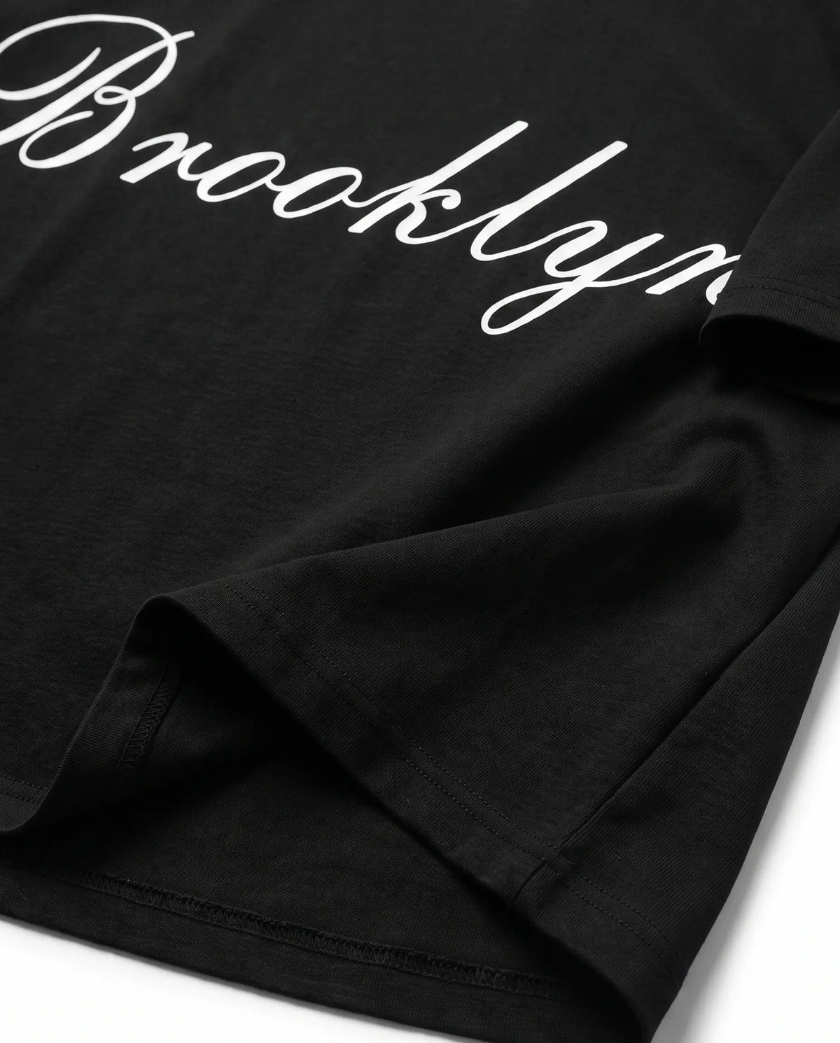 Detalhe da barra e da manga da camiseta oversized preta Brooklyn Prison