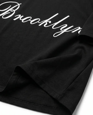 Detalhe da barra e da manga da camiseta oversized preta Brooklyn Prison