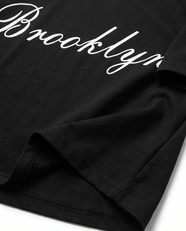 Detalhe da barra e da manga da camiseta oversized preta Brooklyn Prison