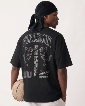 Modelo com bola de basquete vestindo a camiseta oversized NY Varsity Prison preta.
