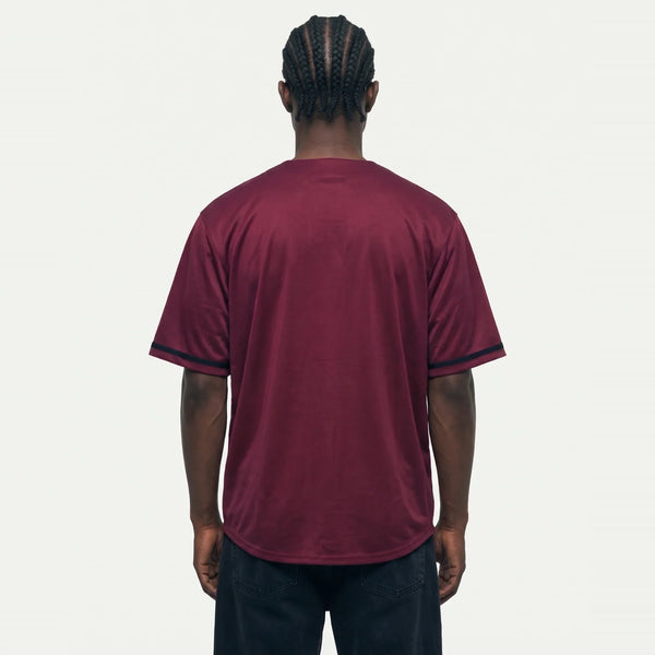 Jhon-1 veste a Camisa de Baseball Jersey 23 Vinho PRISON® de costas, sem estampa, com acabamentos pretos nas mangas e calça preta.
