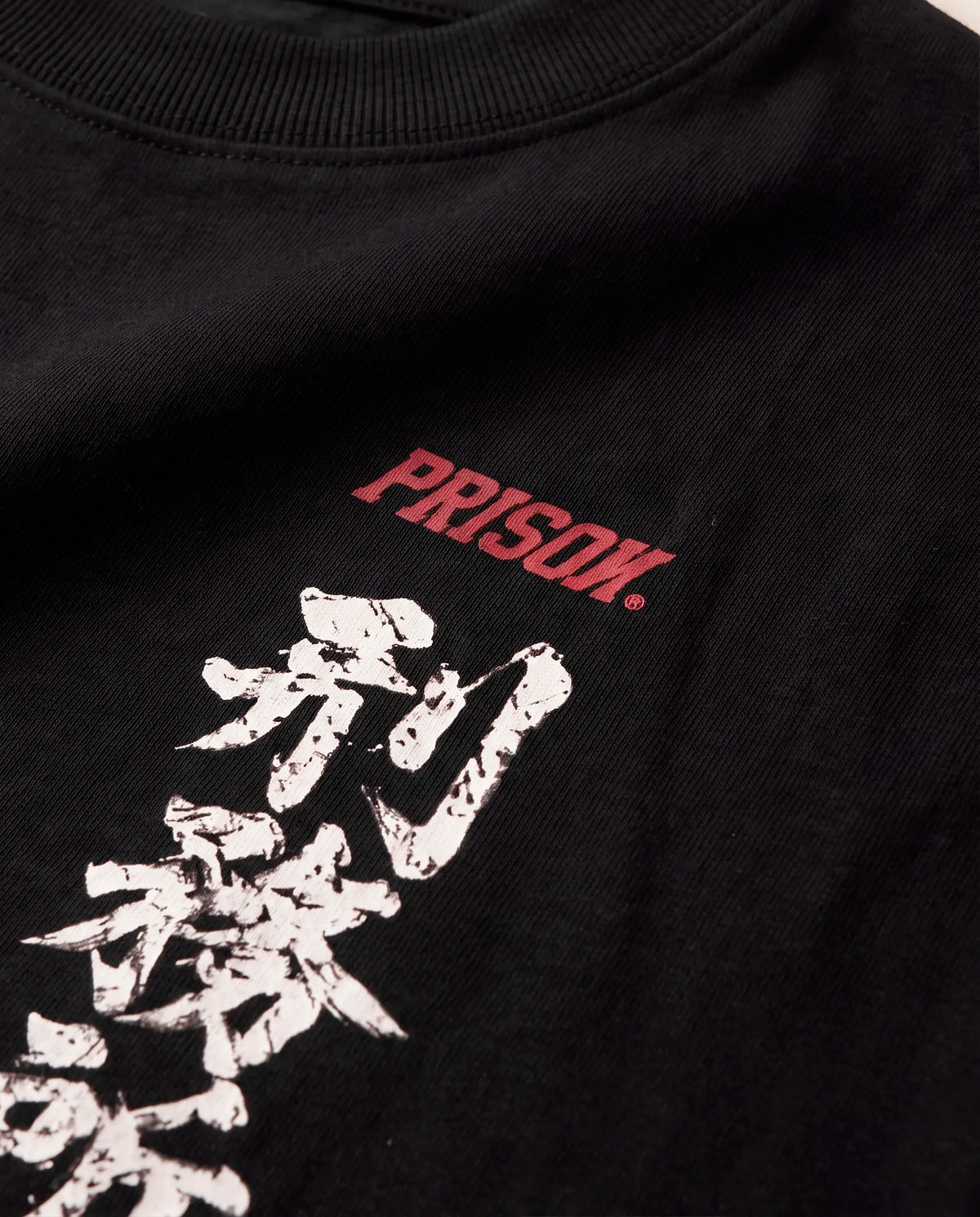 Detalhe da estampa frontal com kanji e assinatura Prison na camiseta oversized Kitsune preta.