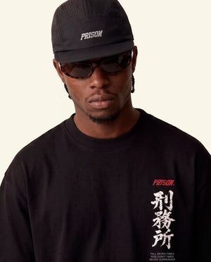 Modelo vestindo a camiseta oversized Kitsune Prison preta, vista frontal do caimento amplo.