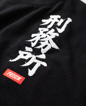 Detalhe da coluna de kanji e assinatura no peito da camiseta oversized Kanji Ink preta.