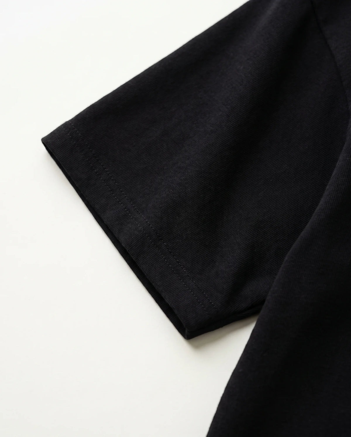 Detalhe da manga e da malha de algodão da camiseta oversized Kanji Ink Prison preta.