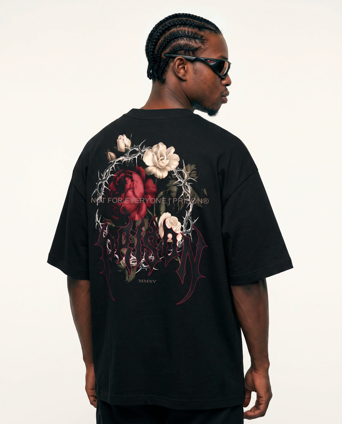 Modelo de costas com o floral de rosas e espinhos da camiseta oversized Thorns Prison preta.