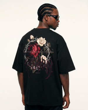 Modelo de costas com o floral de rosas e espinhos da camiseta oversized Thorns Prison preta.
