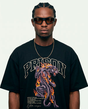 Modelo vestindo a camiseta oversized Panther Fire Prison preta com estampa frontal em roxo.