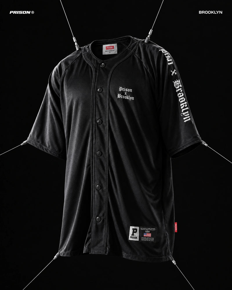 Camisa baseball Brooklyn preta PRISON® com modelagem oversized, mangas raglan e estampa branca, suspensa por cabos.