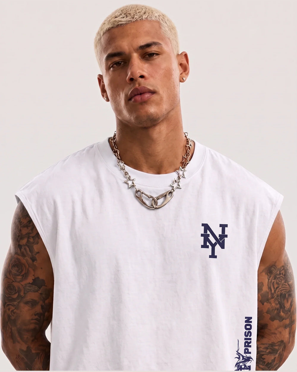 Modelo usando a Regata Machão Tribal NY branca PRISON®, com monograma NY e arte tribal posicionados à direita na vista frontal.